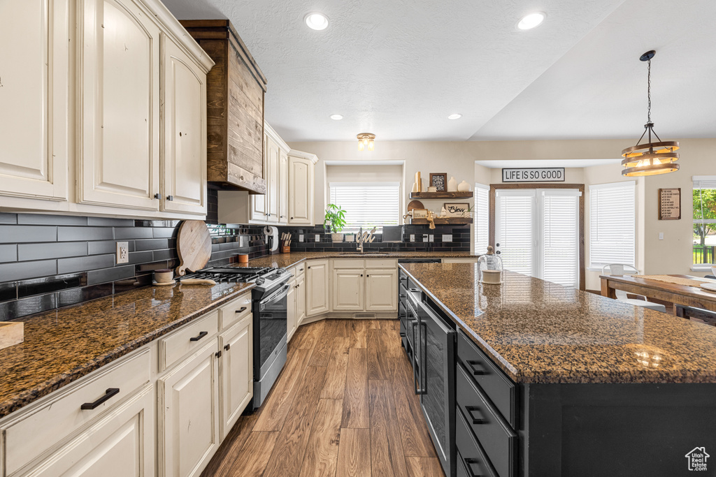 Kitchen with plenty of natural light, decorative backsplash, wood-type flooring, and stainless steel gas range oven