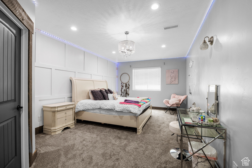 Carpeted bedroom with a notable chandelier and ornamental molding