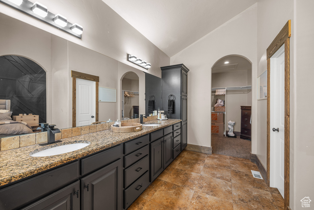 Bathroom with dual vanity, tile patterned floors, and vaulted ceiling