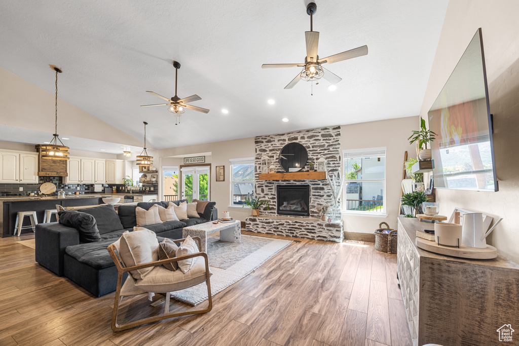 Living room featuring a stone fireplace, light wood-type flooring, and ceiling fan