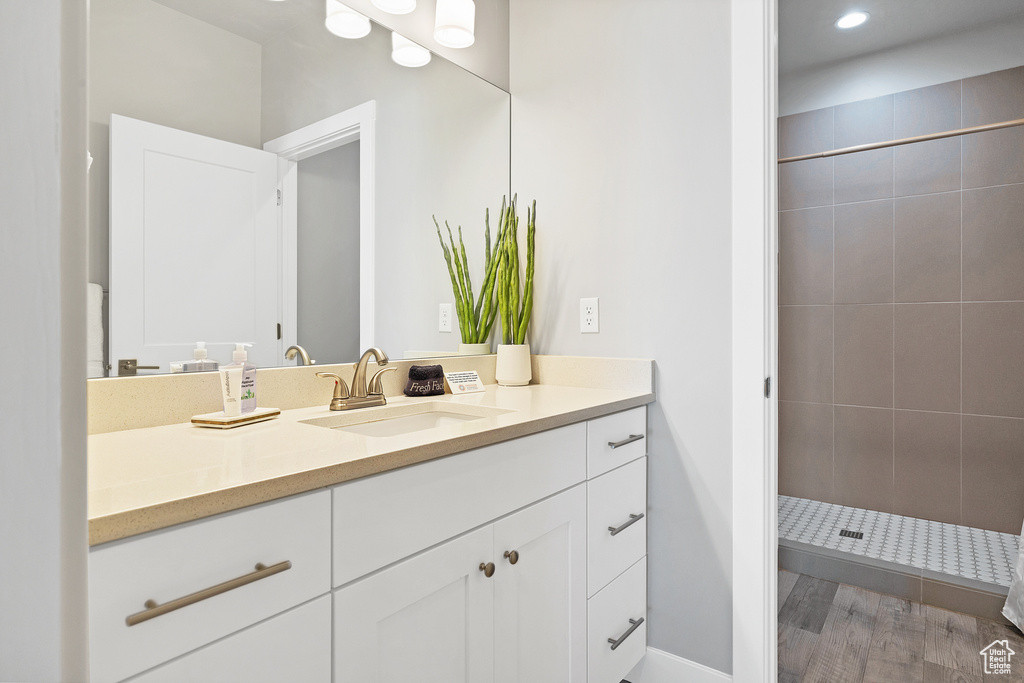 Bathroom with hardwood / wood-style floors, vanity, and a tile shower