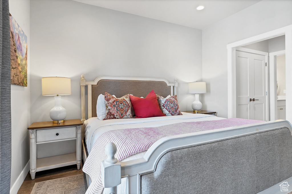 Bedroom with ensuite bathroom and dark hardwood / wood-style flooring