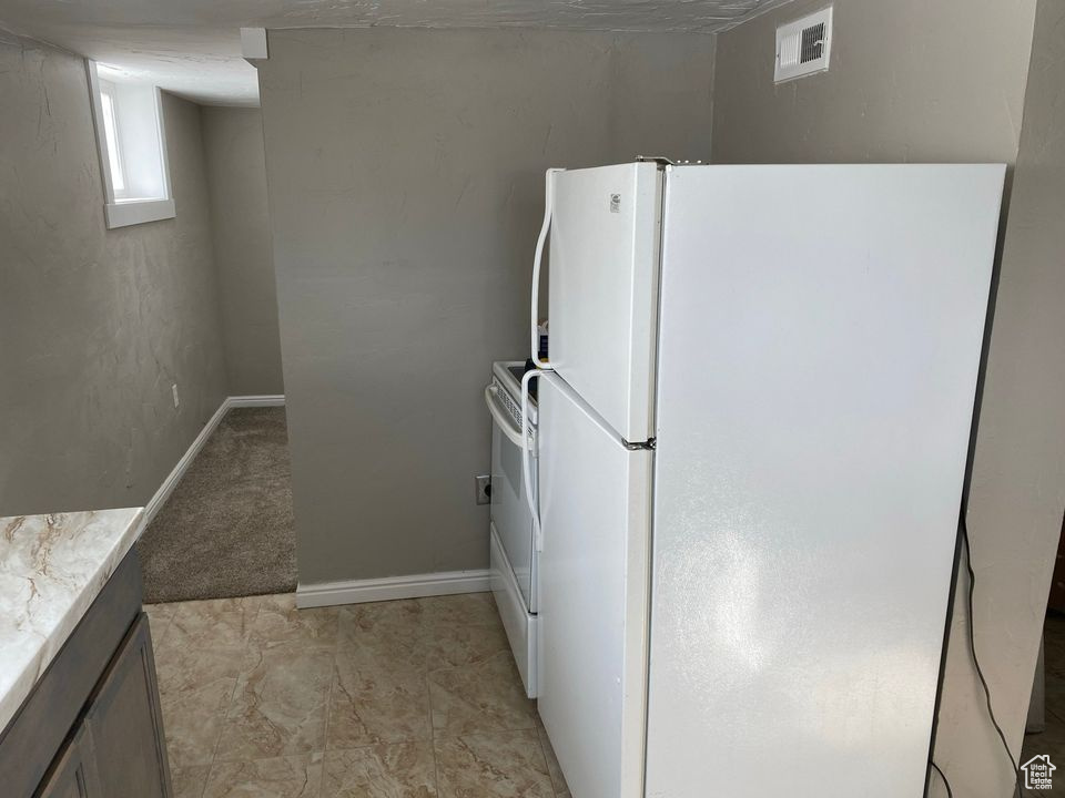 Kitchen with white appliances and light tile floors