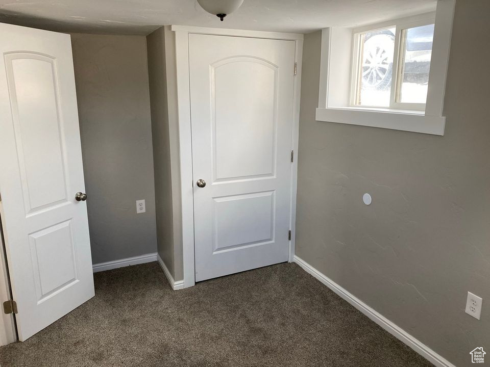 Unfurnished bedroom with dark colored carpet