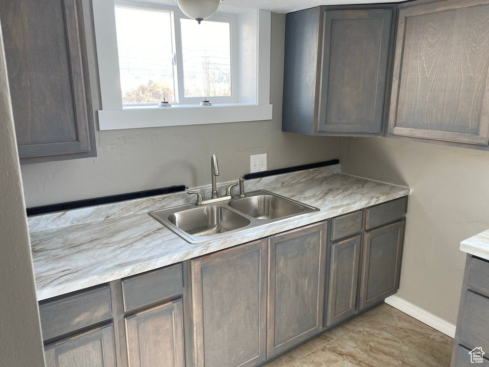 Kitchen with dark brown cabinetry, sink, and light tile flooring