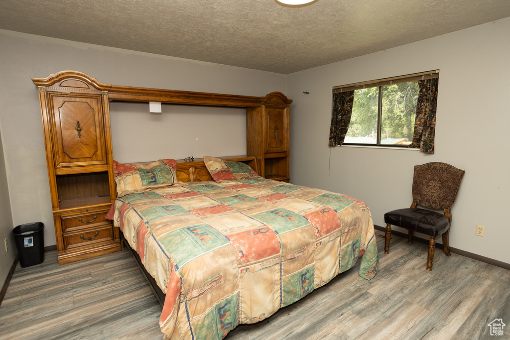 Bedroom with a textured ceiling and hardwood / wood-style floors