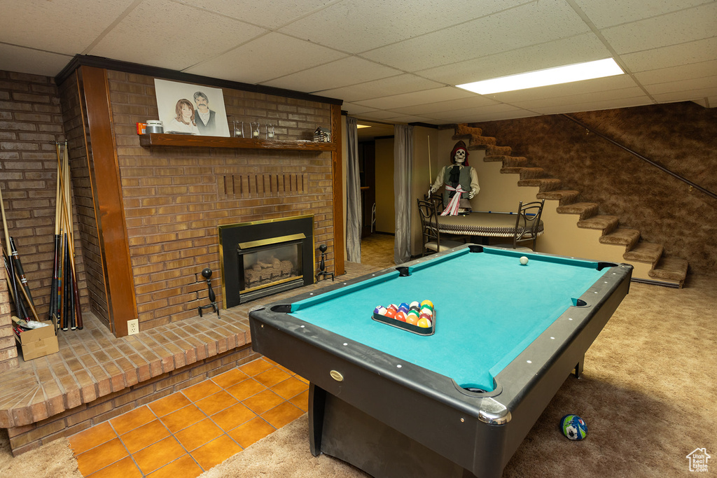 Game room with pool table, a drop ceiling, a fireplace, and brick wall