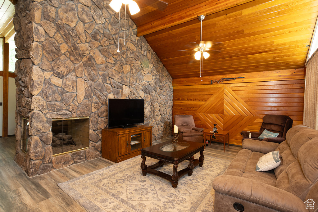 Living room featuring hardwood / wood-style floors, lofted ceiling, wooden walls, and ceiling fan