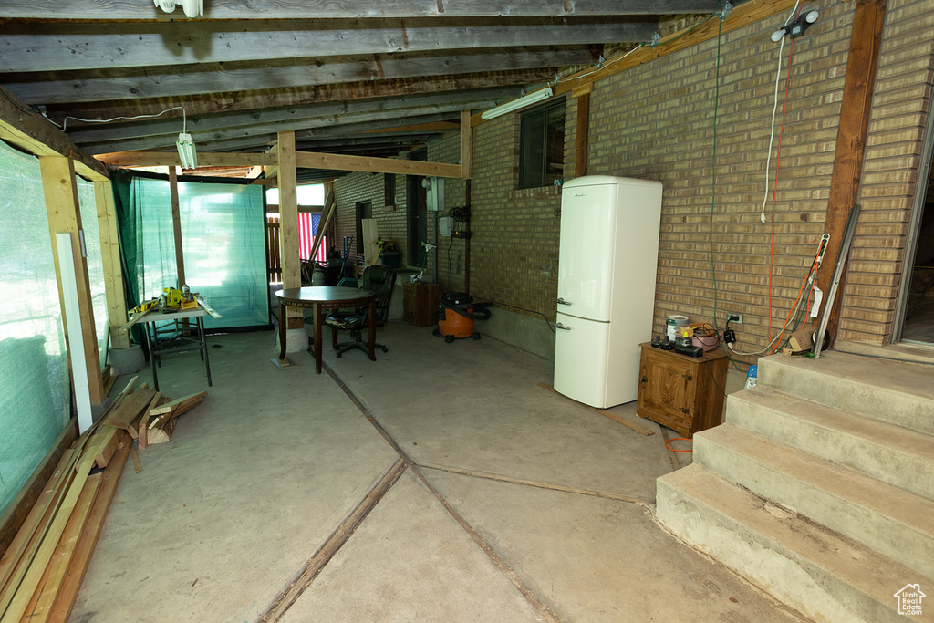 Basement featuring white refrigerator and brick wall