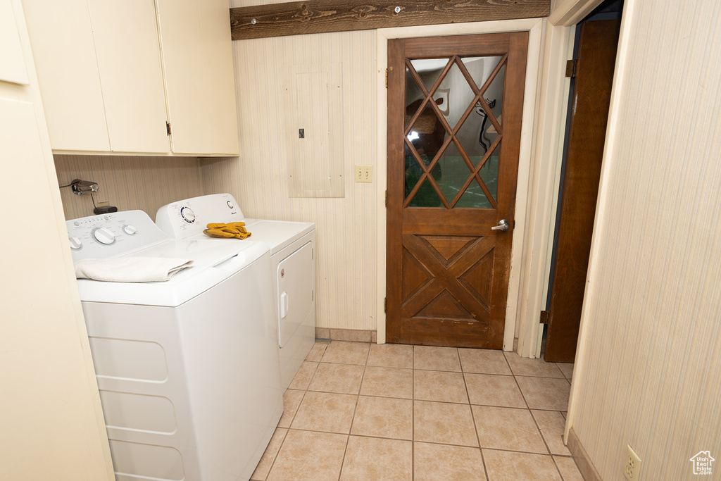 Laundry room featuring independent washer and dryer, cabinets, and light tile patterned floors