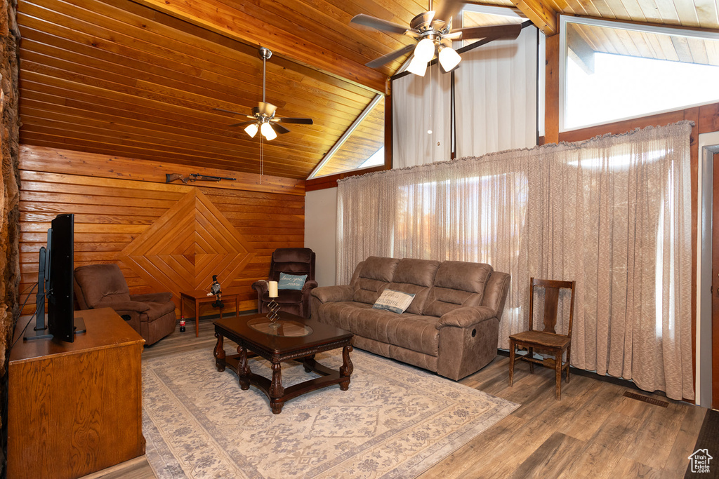 Living room with wood walls, ceiling fan, hardwood / wood-style floors, wooden ceiling, and high vaulted ceiling