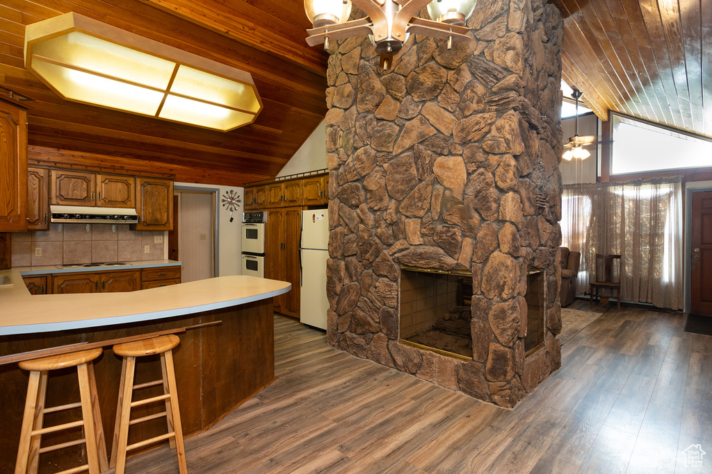 Kitchen with wooden ceiling, dark hardwood / wood-style flooring, a fireplace, and white appliances