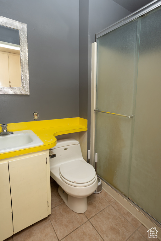 Bathroom featuring a shower with shower door, vanity, tile patterned flooring, and toilet