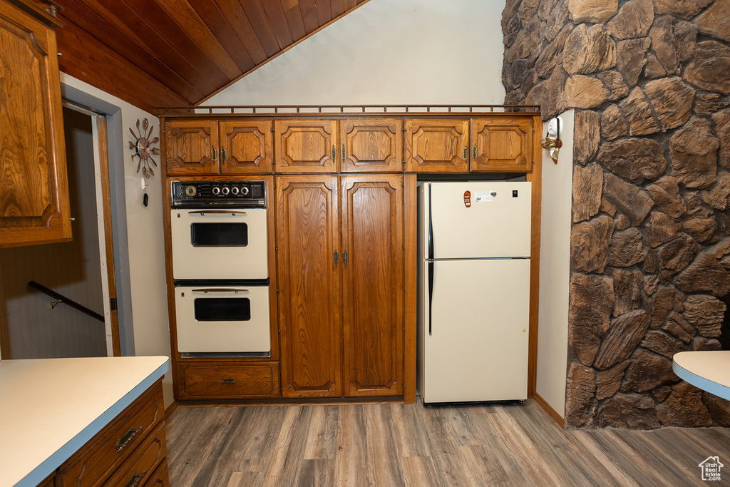 Kitchen with vaulted ceiling, wooden ceiling, hardwood / wood-style floors, and white appliances