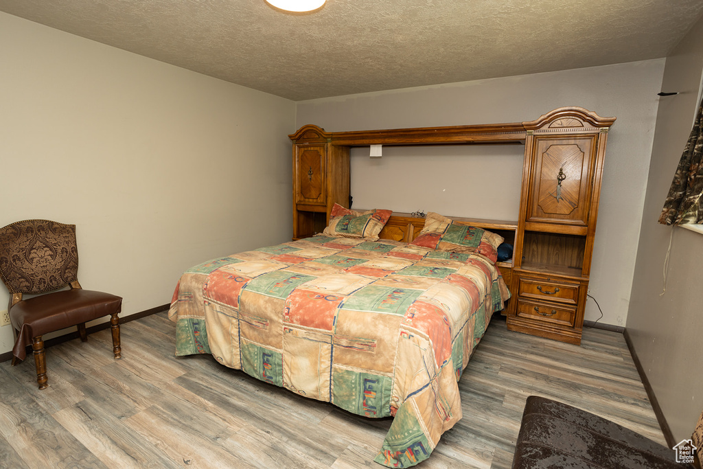 Bedroom with a textured ceiling and hardwood / wood-style floors