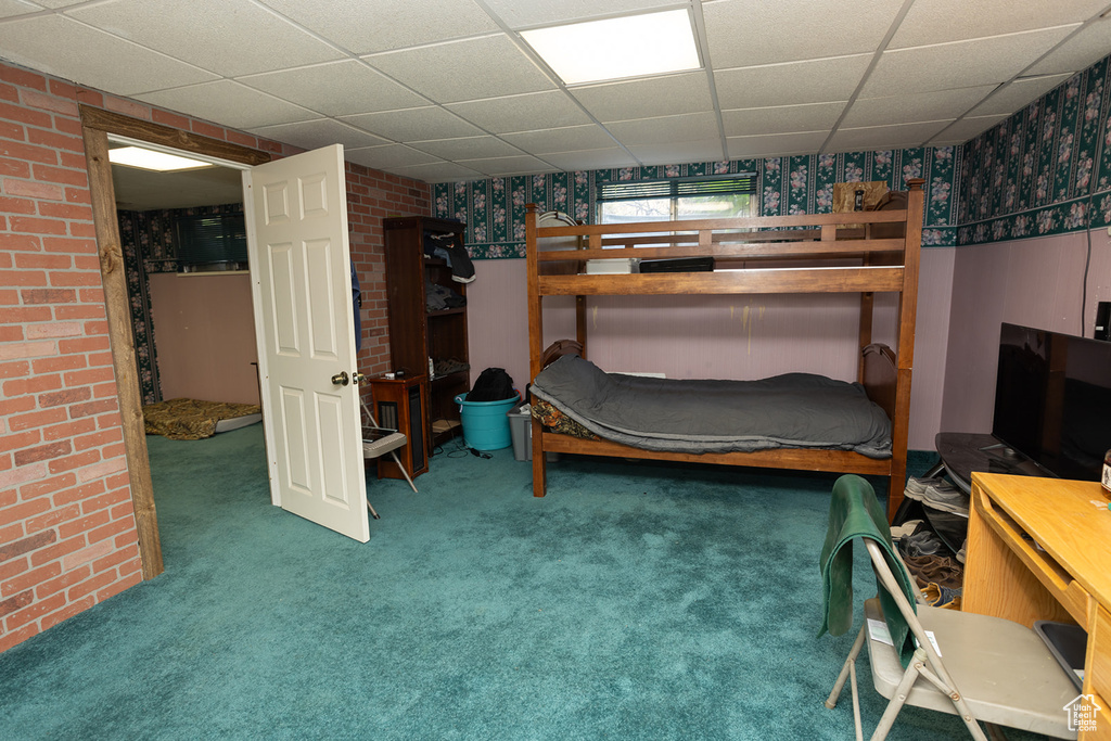 Carpeted bedroom featuring brick wall and a paneled ceiling