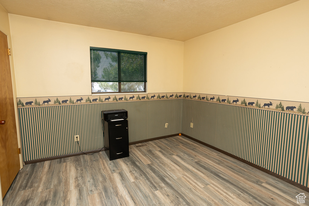 Spare room with wood-type flooring and a textured ceiling