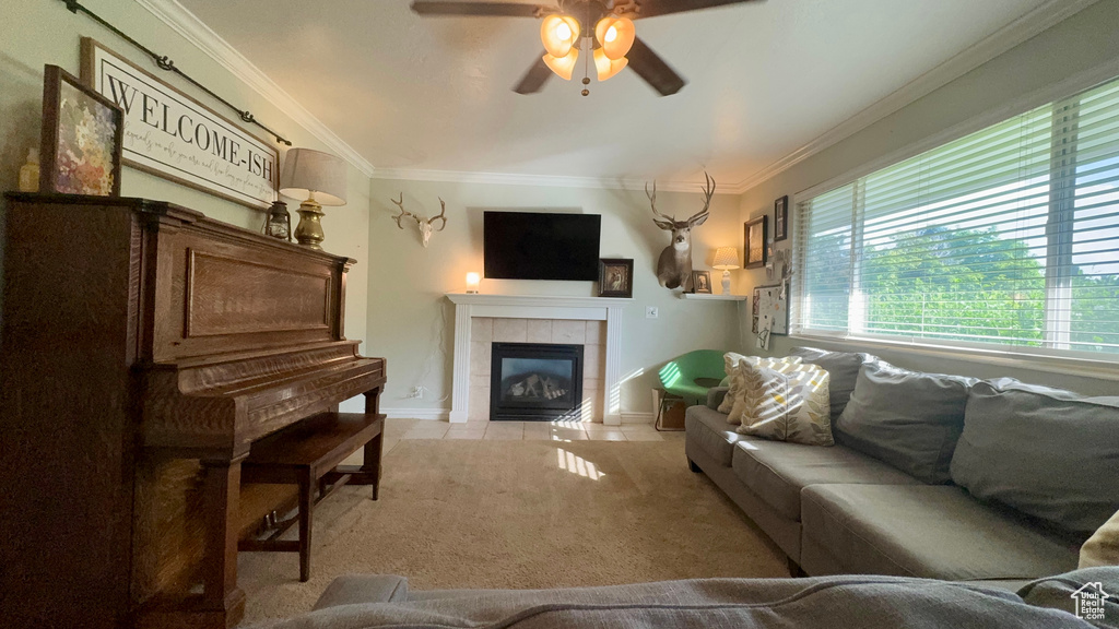 Living room featuring a fireplace, ceiling fan, ornamental molding, and light colored carpet