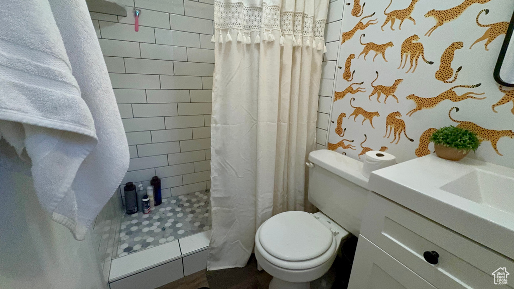 Bathroom featuring curtained shower, toilet, and vanity