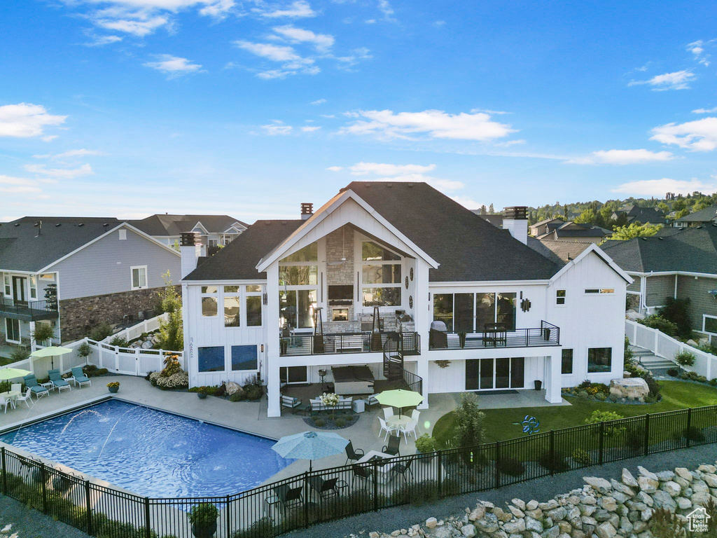 Rear view of property with pool water feature, a patio, and a fenced in pool