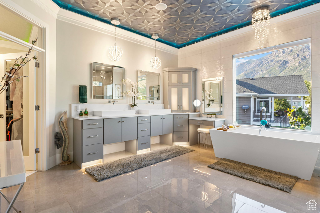 Bathroom with ornamental molding, vanity, an inviting chandelier, and tile patterned flooring