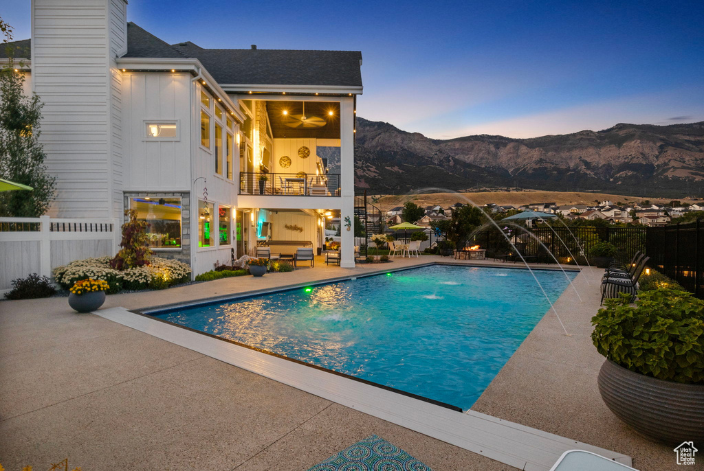 Pool at dusk with a mountain view, a patio, and pool water feature