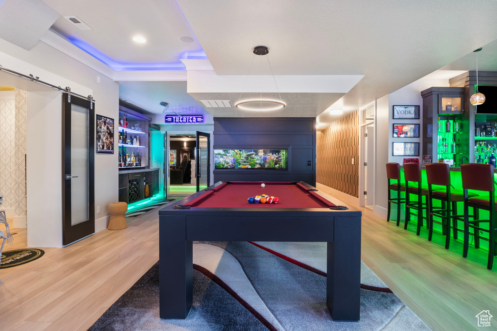 Playroom featuring hardwood / wood-style flooring, a tray ceiling, billiards, indoor bar, and crown molding