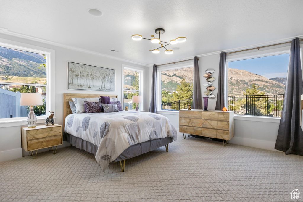 Carpeted bedroom with crown molding, a notable chandelier, and multiple windows