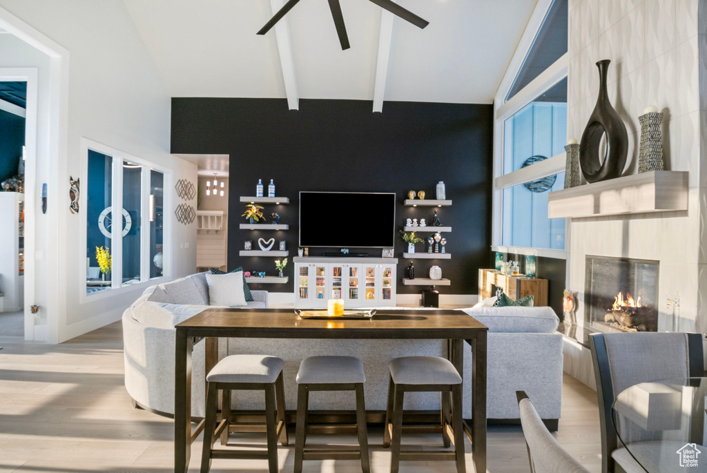 Living room featuring light hardwood / wood-style floors, high vaulted ceiling, a fireplace, and beamed ceiling