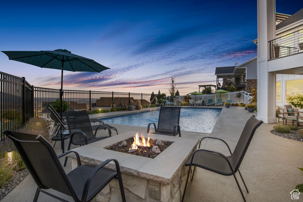 Pool at dusk with a patio area and an outdoor fire pit