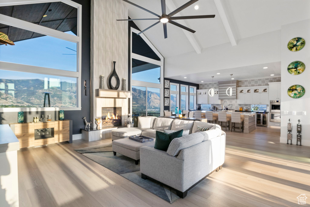 Living room with light hardwood / wood-style floors, a multi sided fireplace, ceiling fan, and high vaulted ceiling