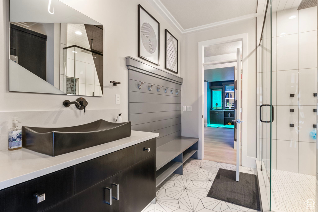 Bathroom featuring walk in shower, tile patterned floors, crown molding, and vanity