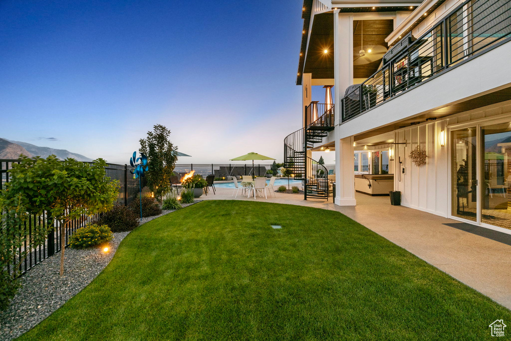 Yard at dusk with a patio area and a fenced in pool