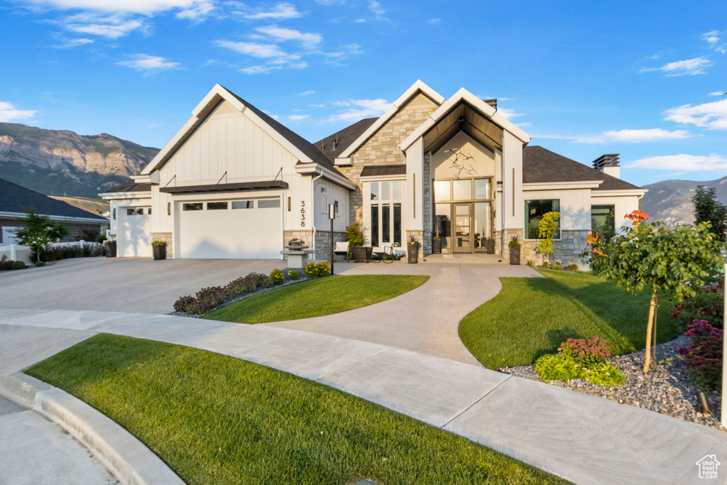 View of front facade with a garage, a mountain view, and a front yard