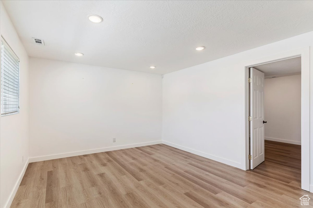 Unfurnished room with light hardwood / wood-style flooring and a textured ceiling