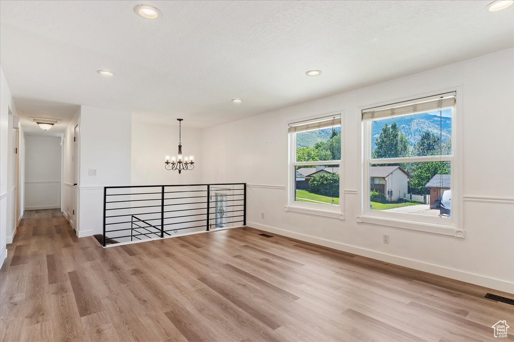 Empty room featuring wood-type flooring and a chandelier