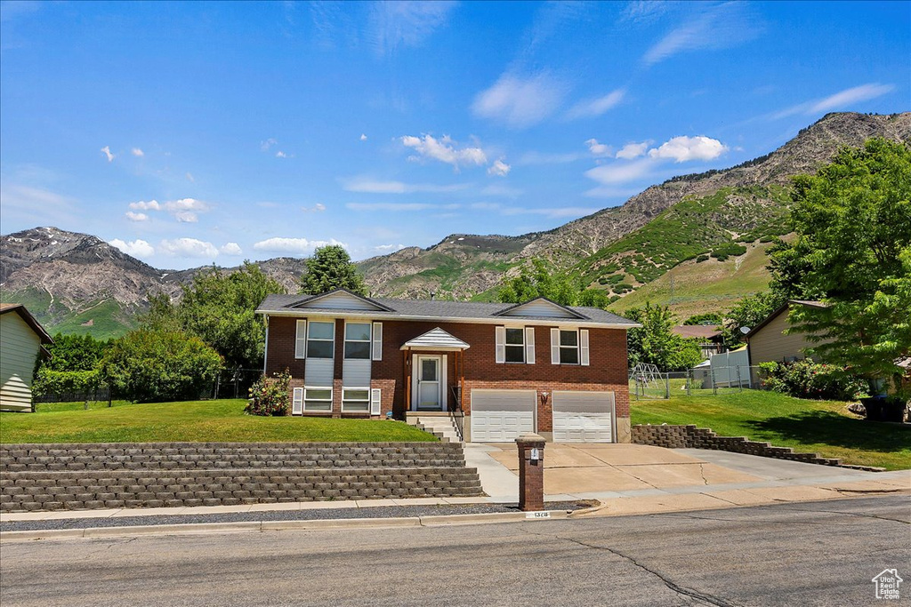 Bi-level home with a mountain view, a garage, and a front lawn