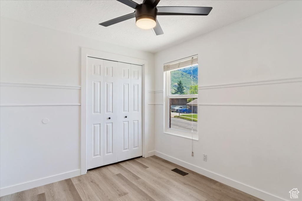 Unfurnished bedroom with light hardwood / wood-style flooring, a closet, and ceiling fan