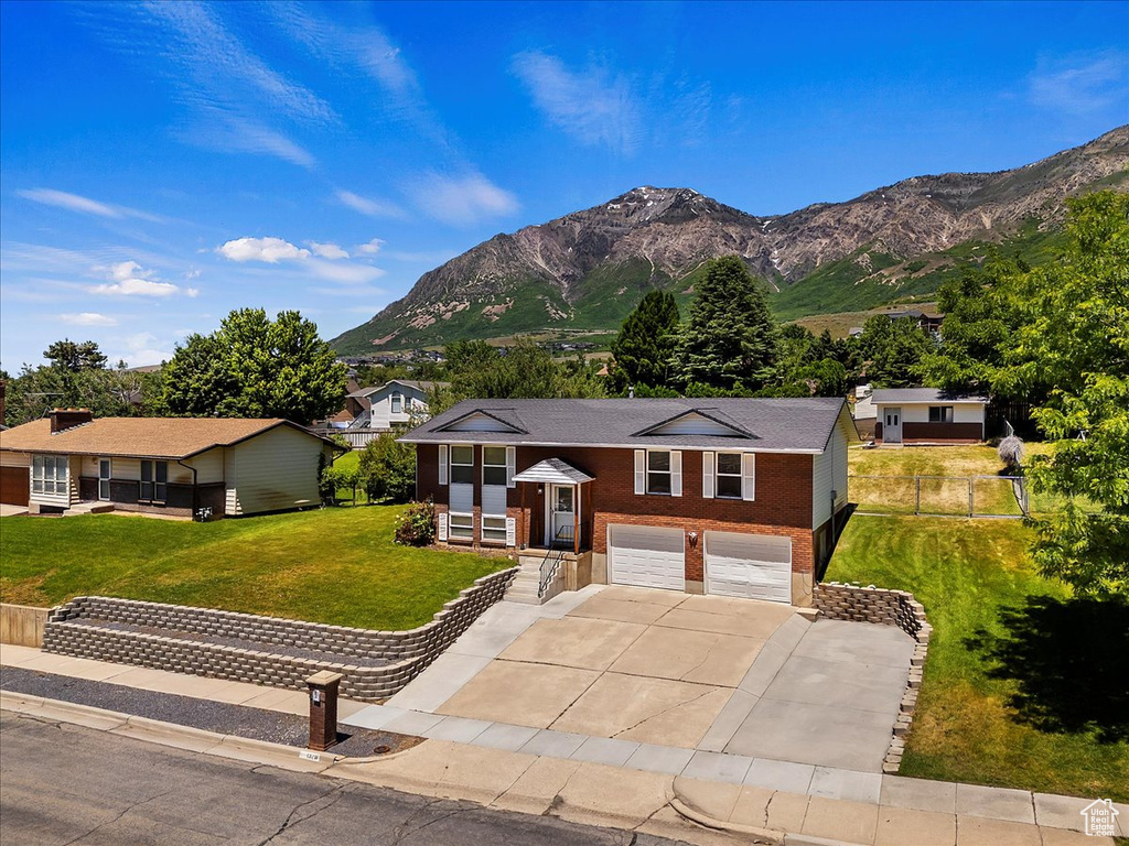 Ranch-style house with a mountain view, a garage, and a front lawn