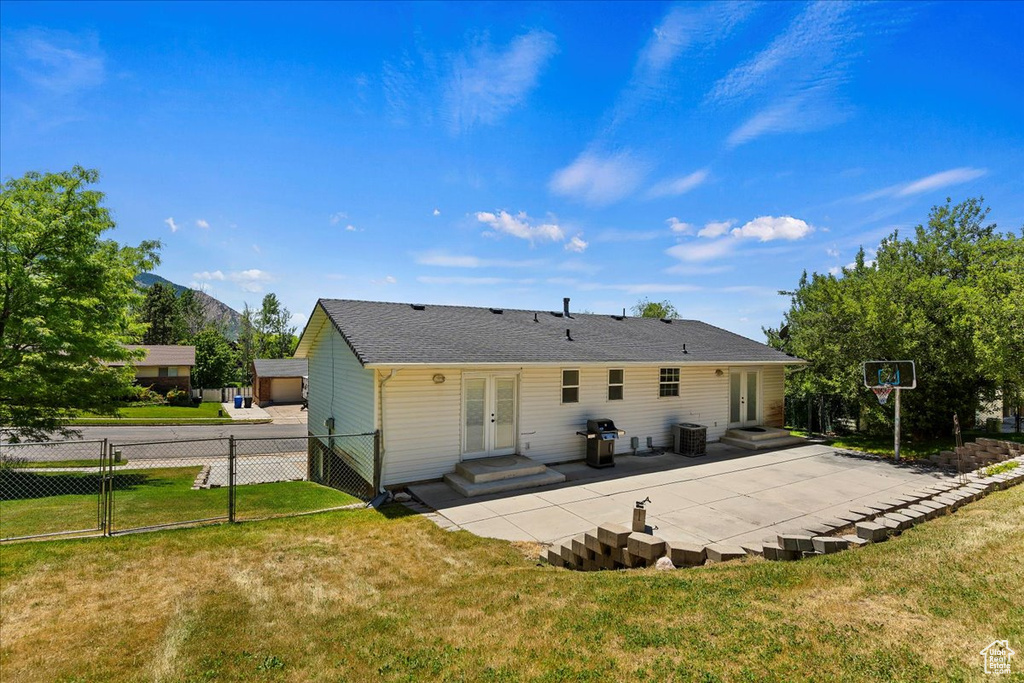 Back of house featuring cooling unit, french doors, a yard, and a patio area