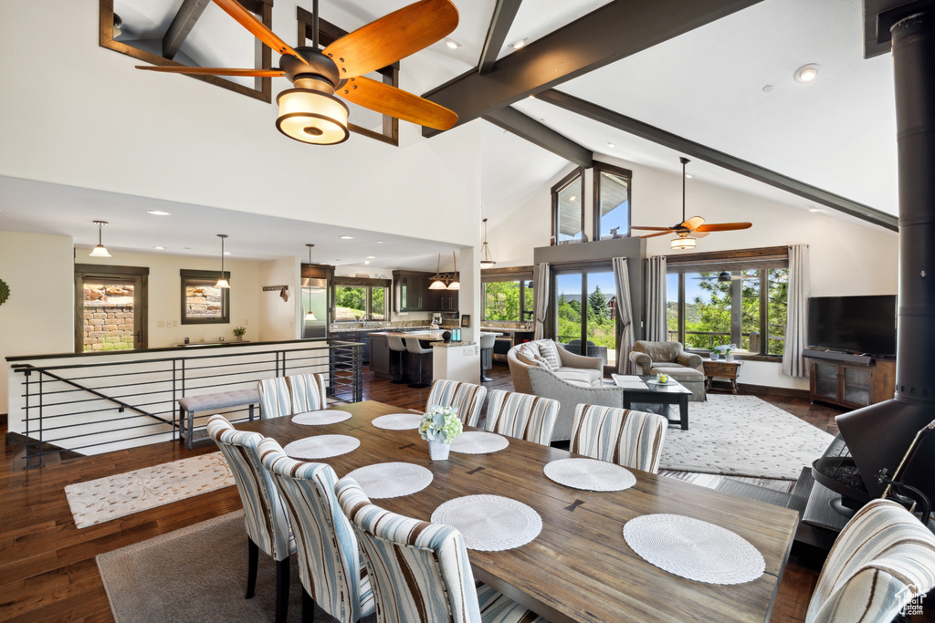 Dining area featuring ceiling fan, high vaulted ceiling, a wood stove, and a wealth of natural light