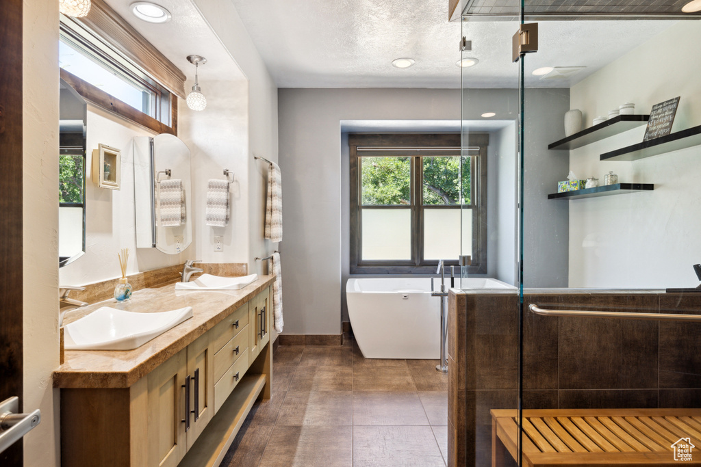 Bathroom featuring vanity, tile patterned flooring, a textured ceiling, and a washtub