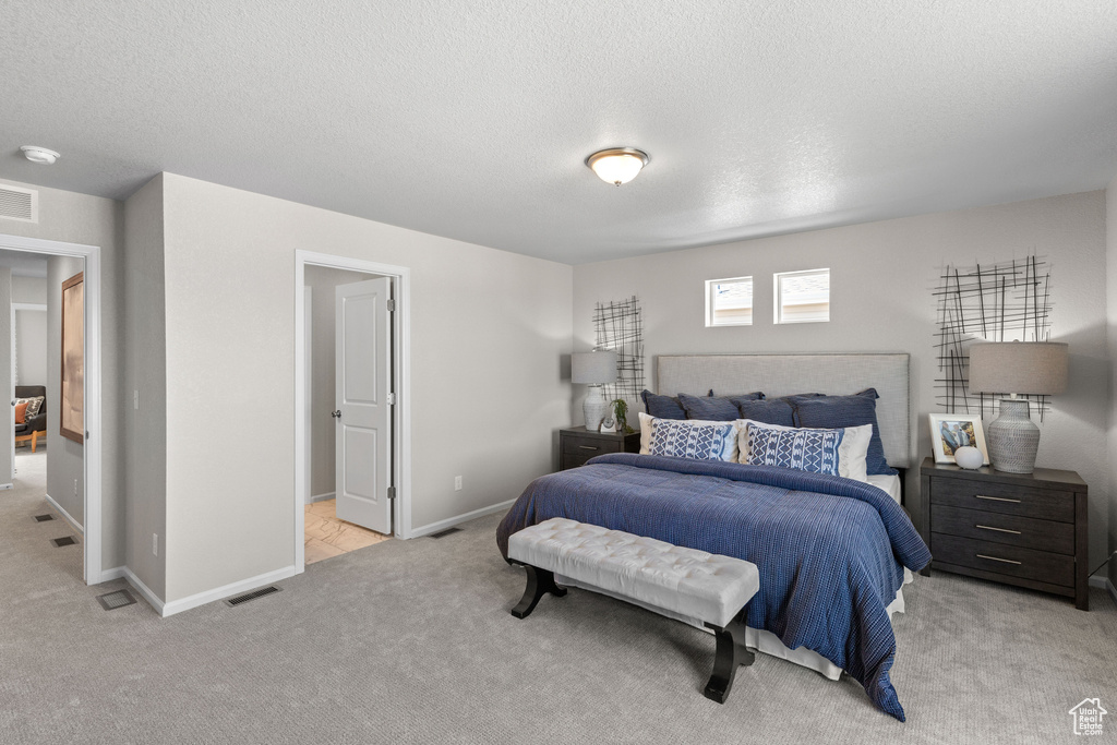 Bedroom with a textured ceiling and light colored carpet