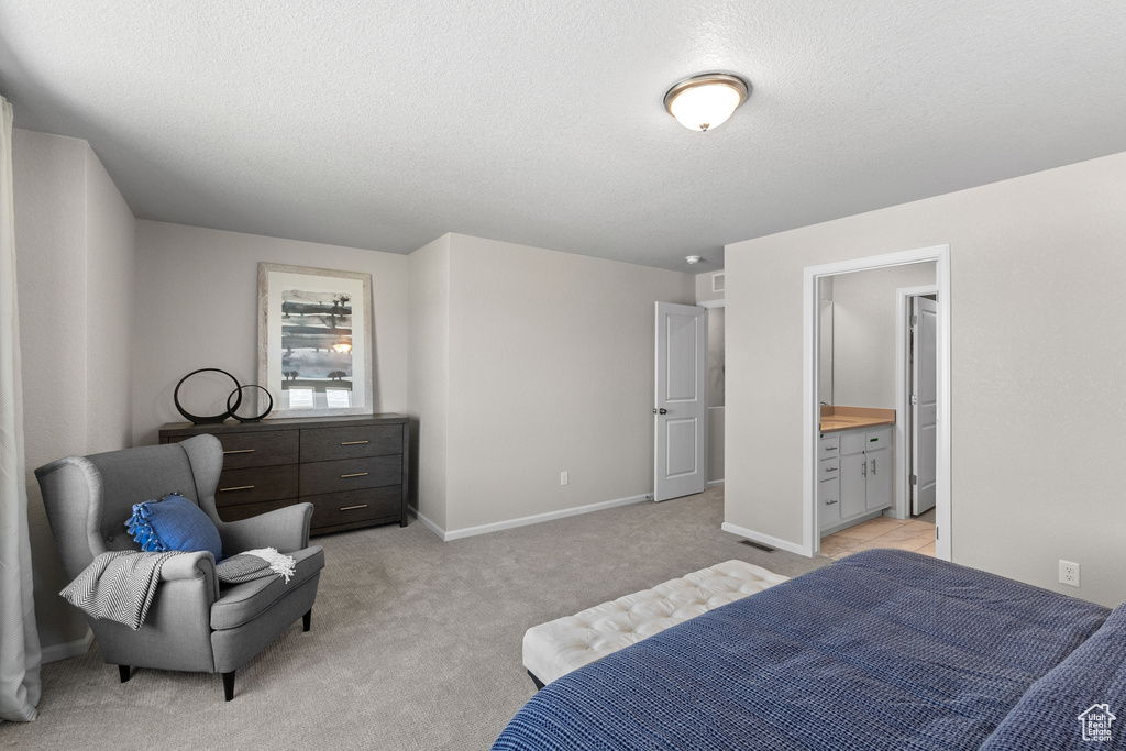 Bedroom featuring light carpet, connected bathroom, and a textured ceiling