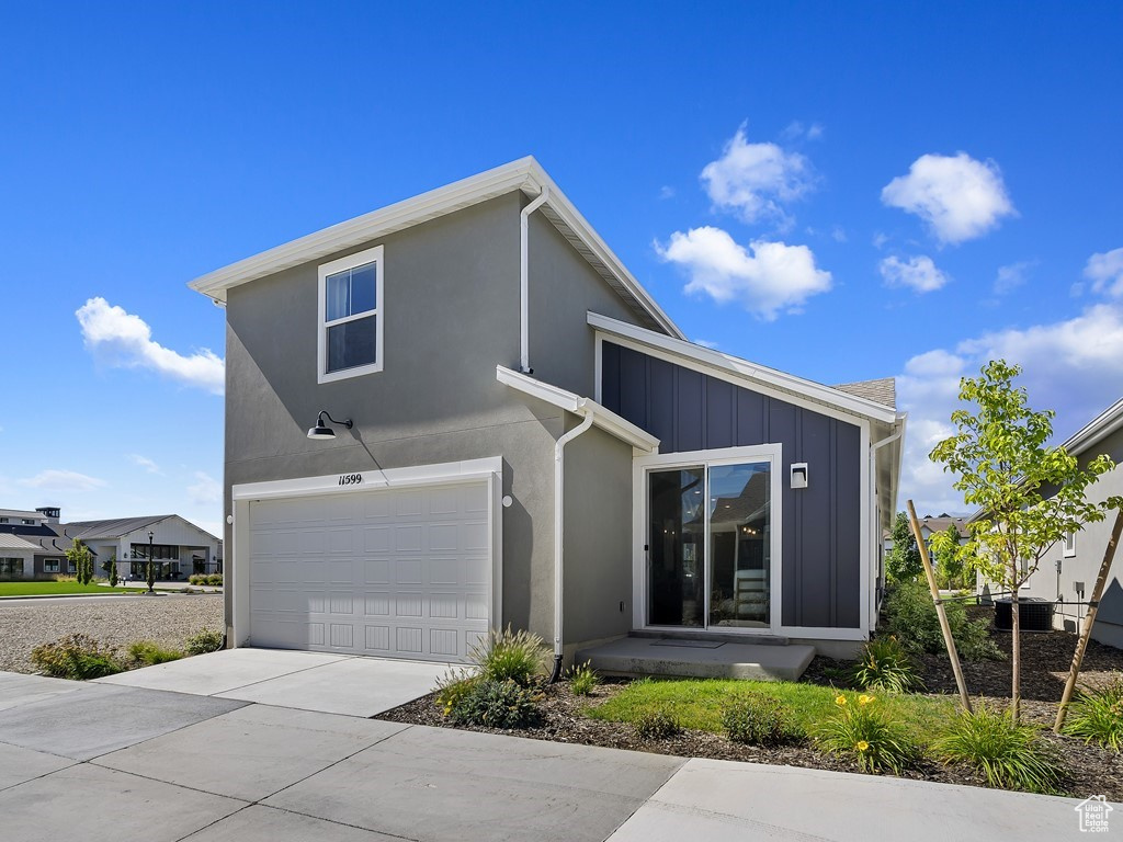 View of front of house with cooling unit and a garage