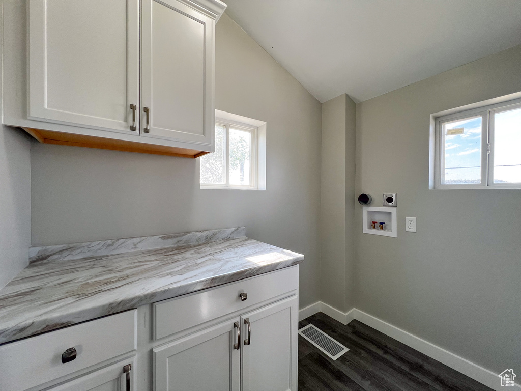 Laundry area with cabinets, hookup for a washing machine, plenty of natural light, and dark wood-type flooring