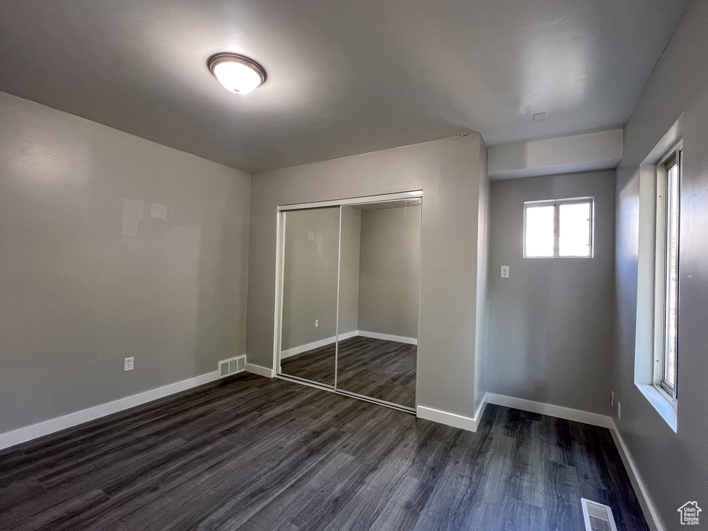 Unfurnished bedroom featuring a closet and dark wood-type flooring