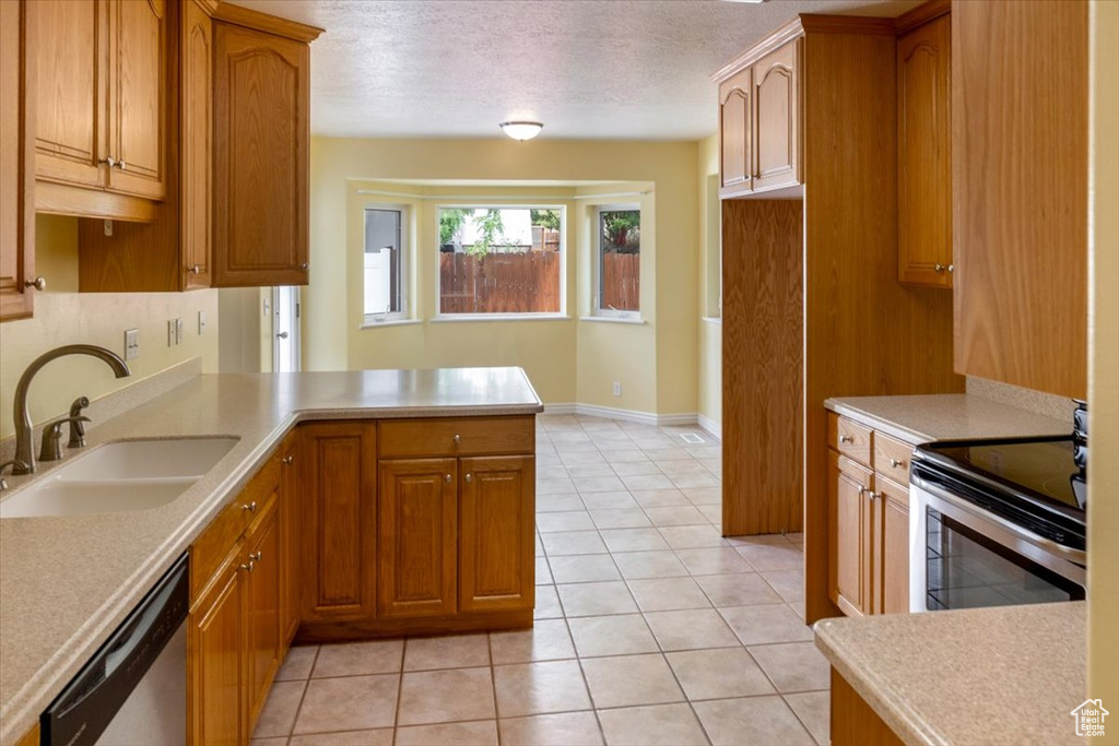 Kitchen featuring light tile patterned floors, sink, appliances with stainless steel finishes, a textured ceiling, and kitchen peninsula