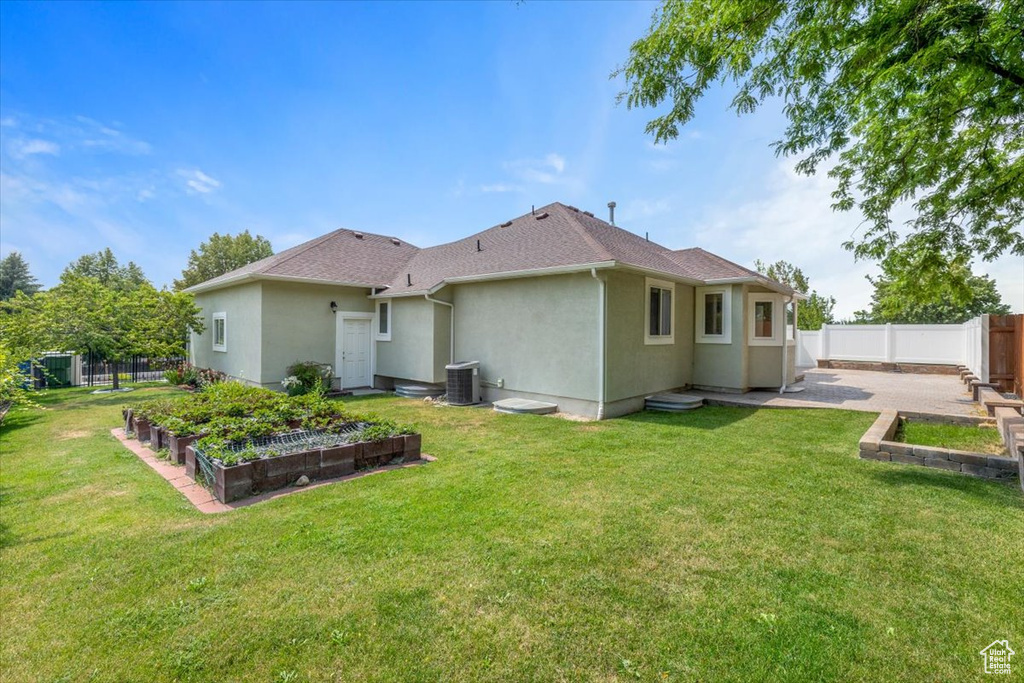 Back of property with a lawn and central AC unit