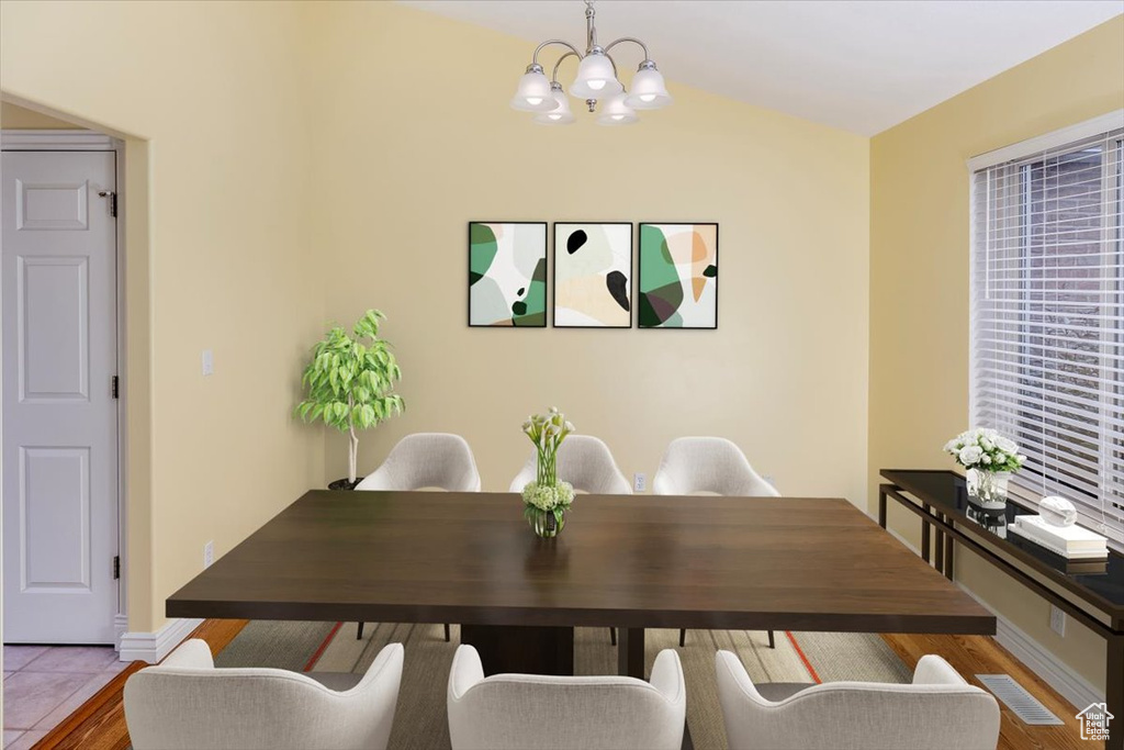 Dining area featuring hardwood / wood-style flooring, lofted ceiling, and a chandelier